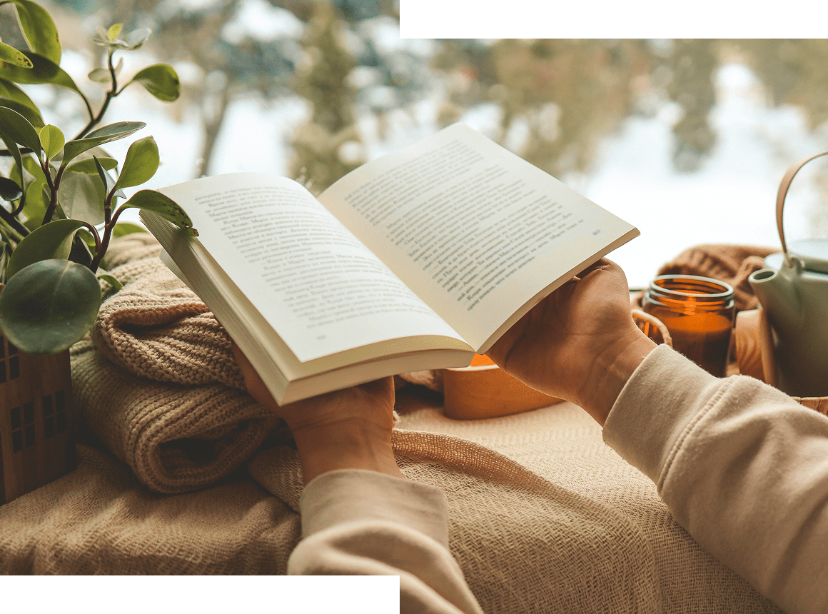 Person reading a book outdoors on a cozy blanket.